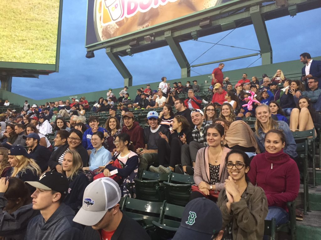 People sitting in bleacher seats while smiling and looking at the camera