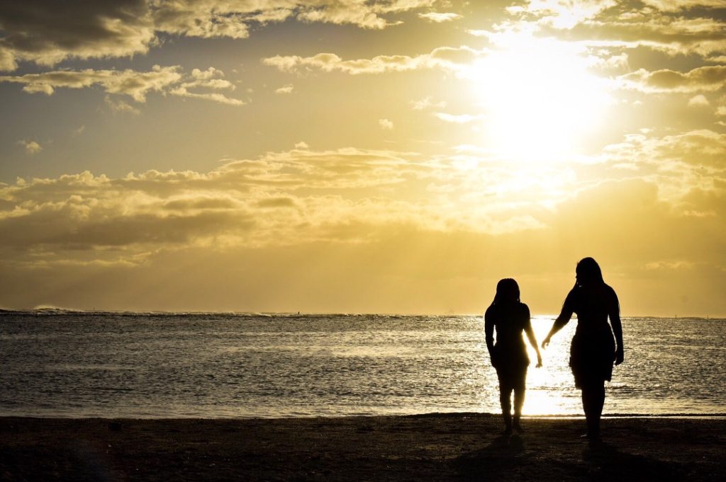 a photo of two people walking into a sunset on a beach in Hawaii