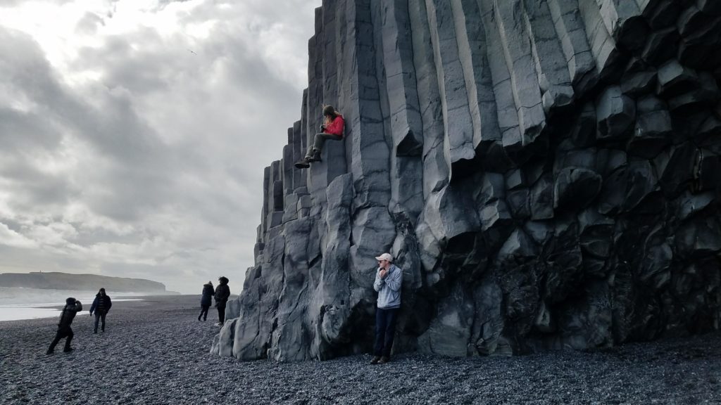 A group photo of people standing in front of a pillar in Iceland