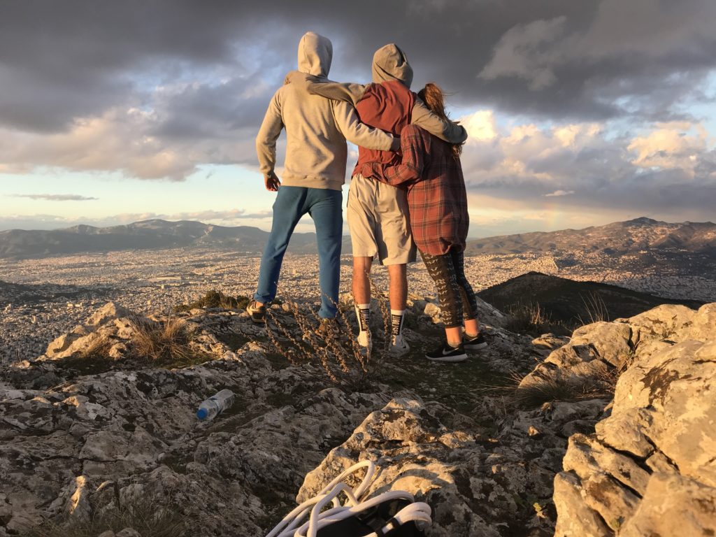 A group photo of people overlooking the city of Athens from a hill