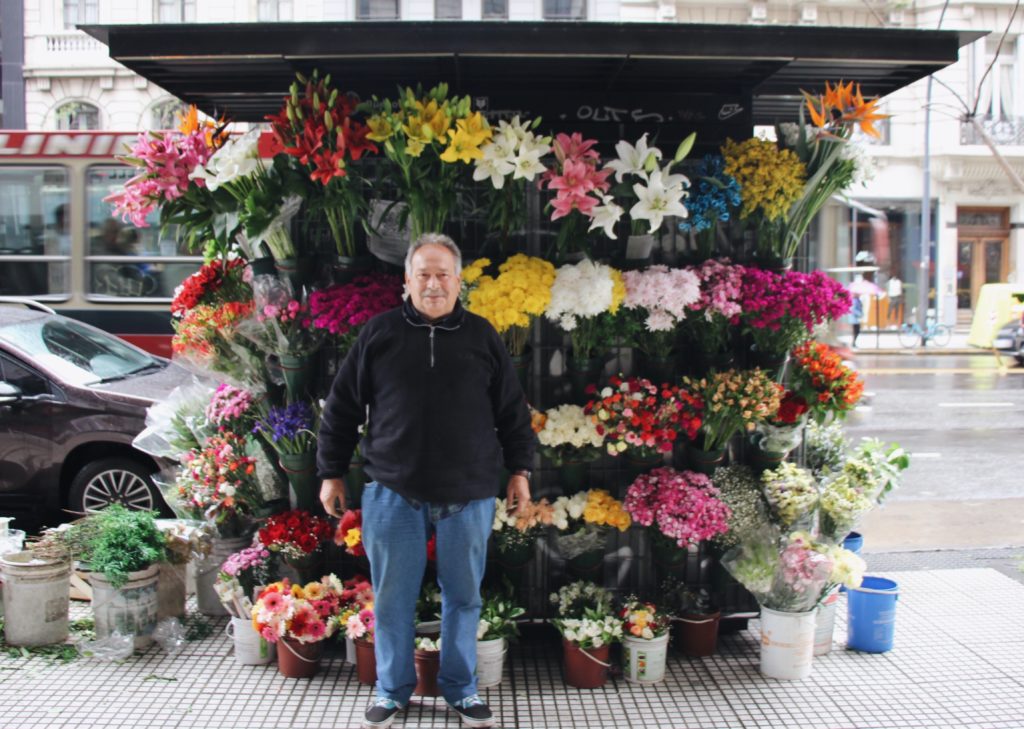 A photo of a man in front of different flowers.