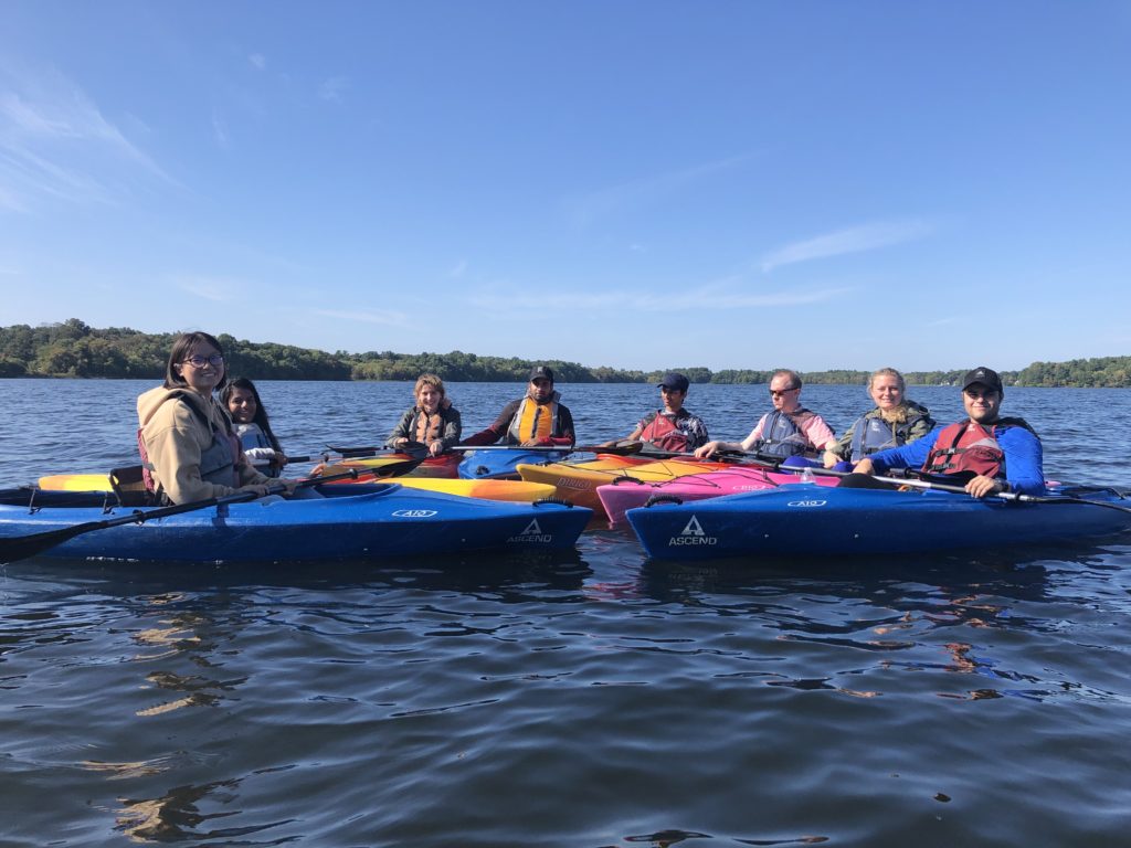 A group of people in kayaks in the river with a blue sky and sunny background