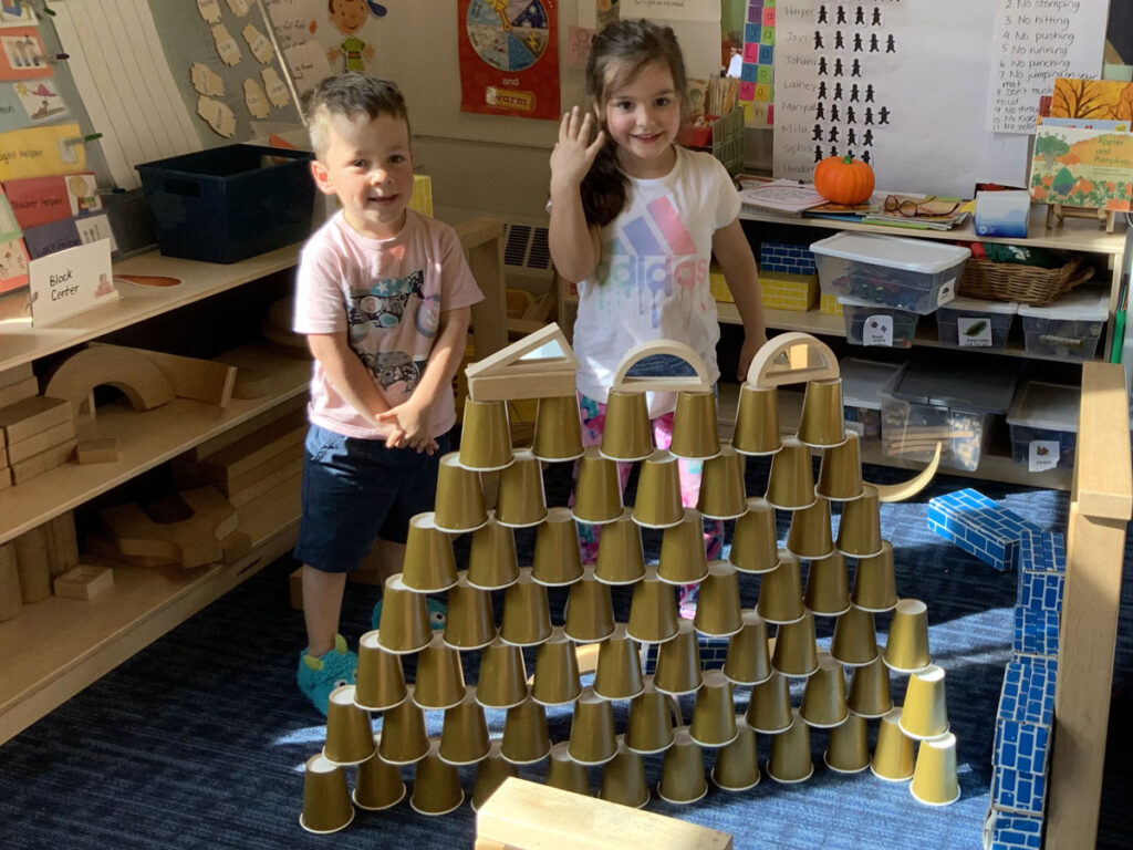 Chidren standing behind a tower made of cups