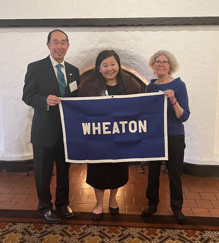 Alumni and friends holding Wheaton flag at T&T event