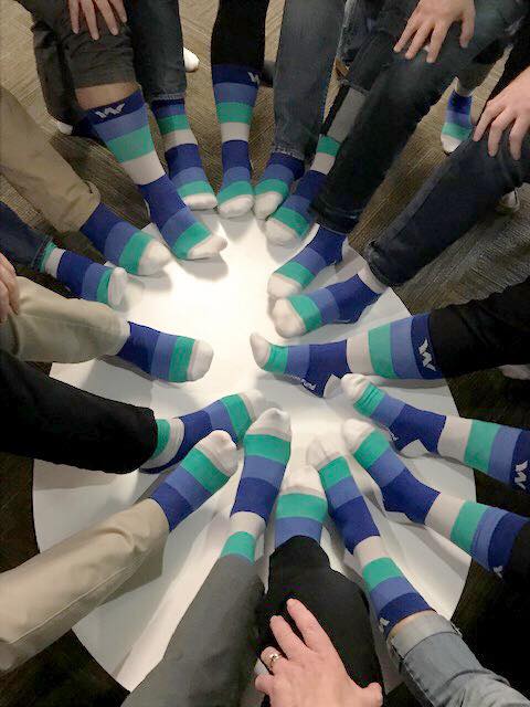Group image of students wearing colorful Wheaton Fund socks with Wheaton logo