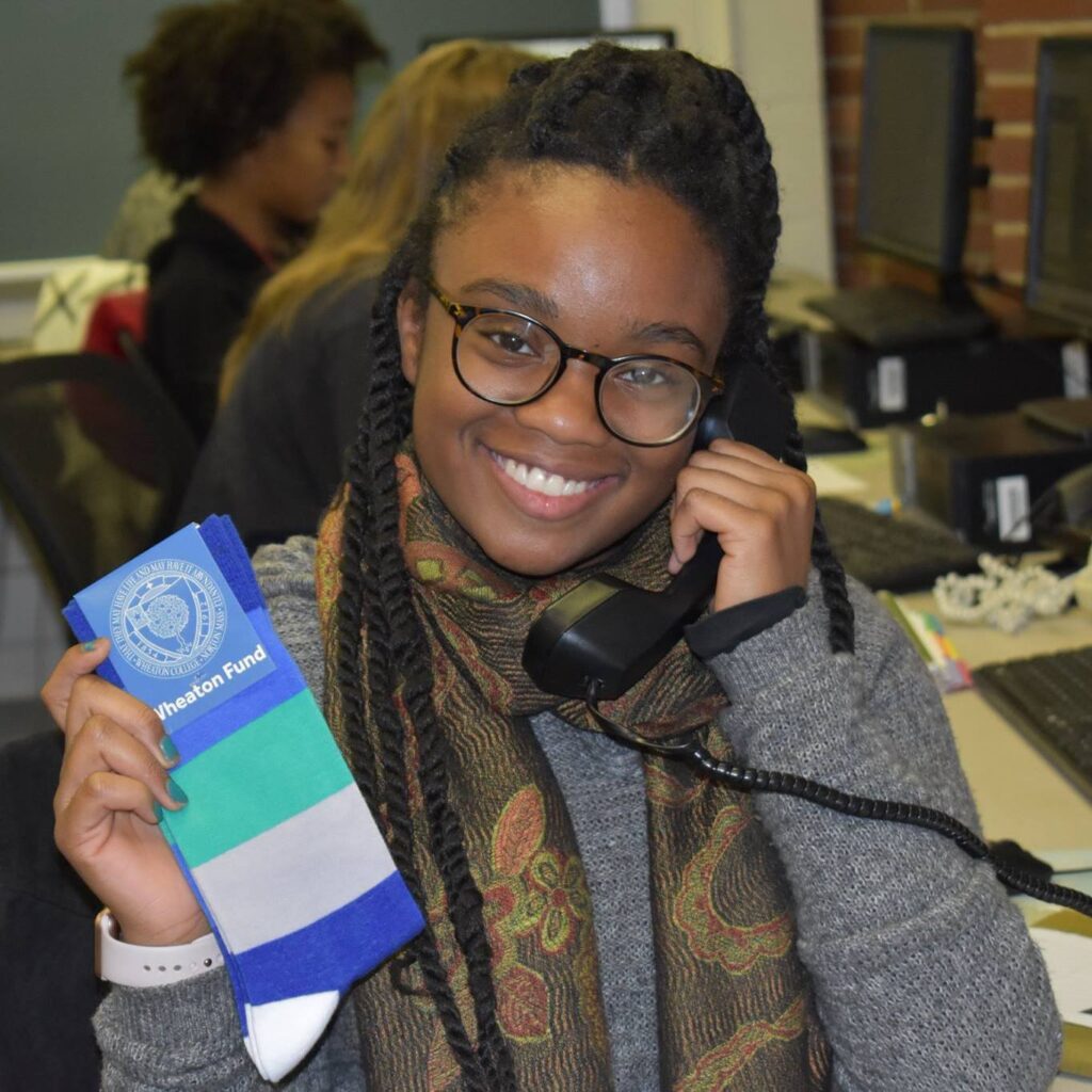 Student on telephone holding Wheaton Fund socks