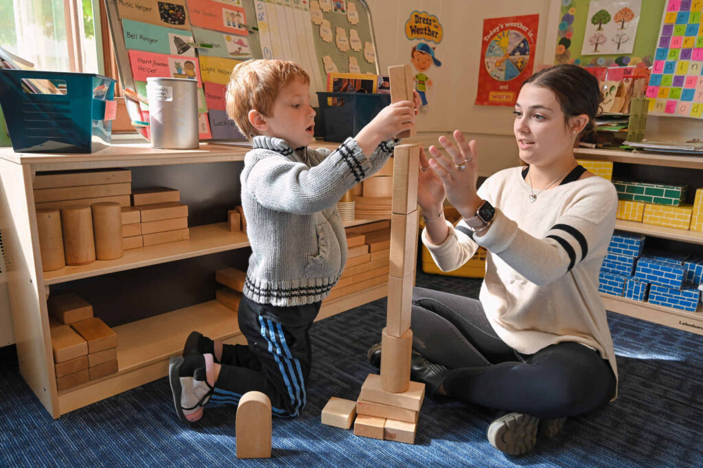 Assistant teacher and child playing with blocks