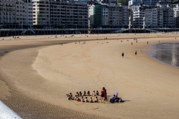 A cluster of people sitting on the sand on a beach.