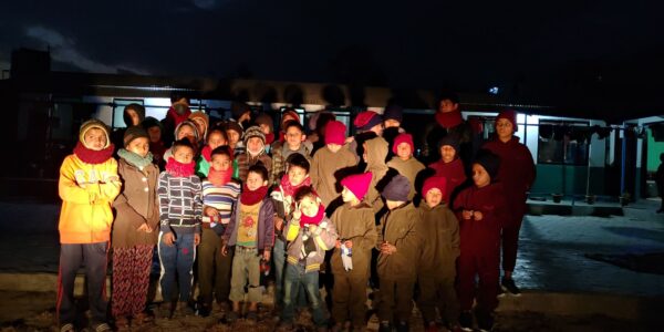 Group of children wearing matching knitted red scarves and hats.