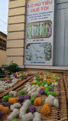 An outdoor stand selling dried noodles in a variety of colors.