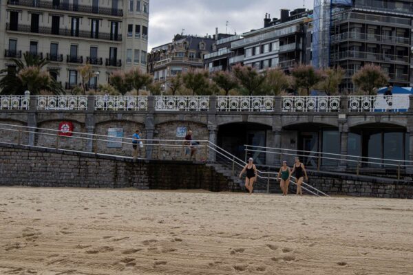 Three women in swimsuits on a beach.