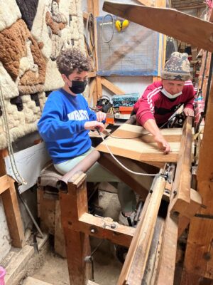 A student and a weaver working on a weaving project together.