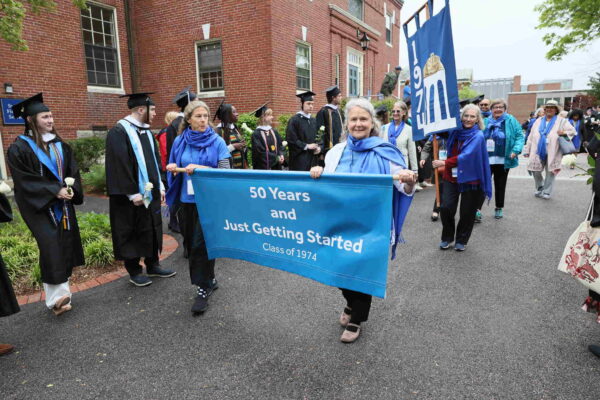 Two members of the Wheaton College Class of 1974 carry a banner