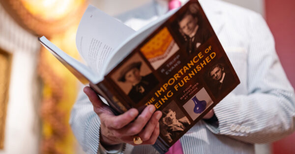 Professor Evans holds open a copy of his book, The Importance of Being Furnished: Four Bachelors at Home.