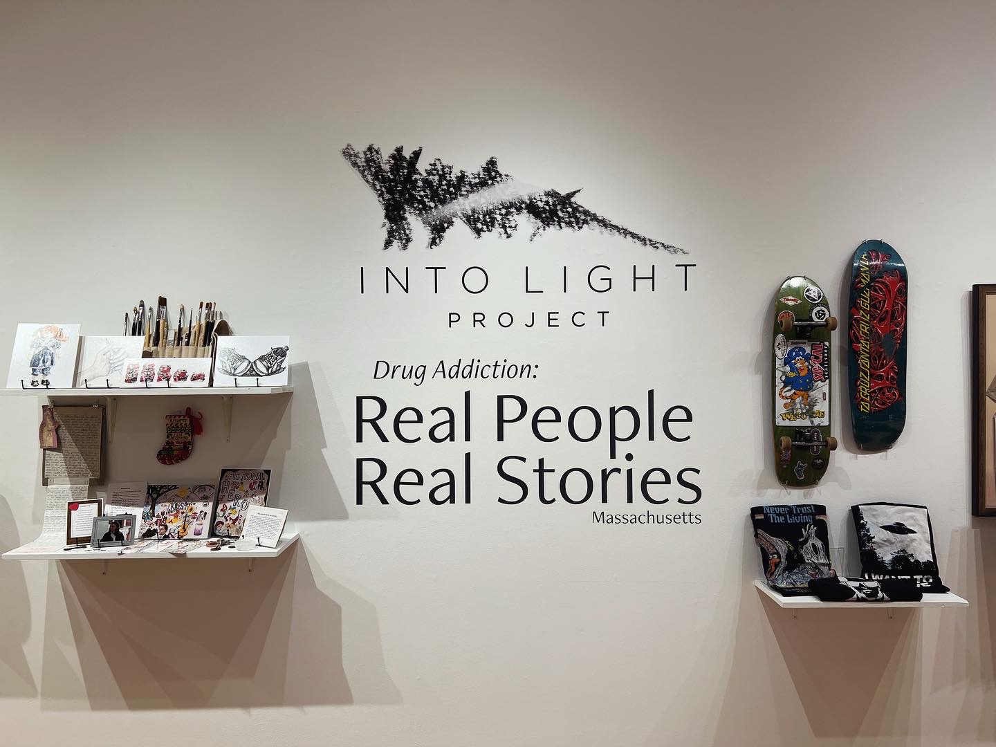 Image from the exhibition with the Into Light logo and personal items from people in honored in the exhibition.