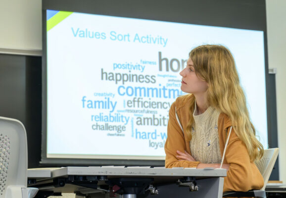 A student with long blond hair sitting at a desk.