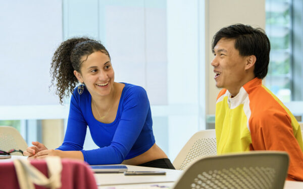 Two students sitting at desks and laughing.