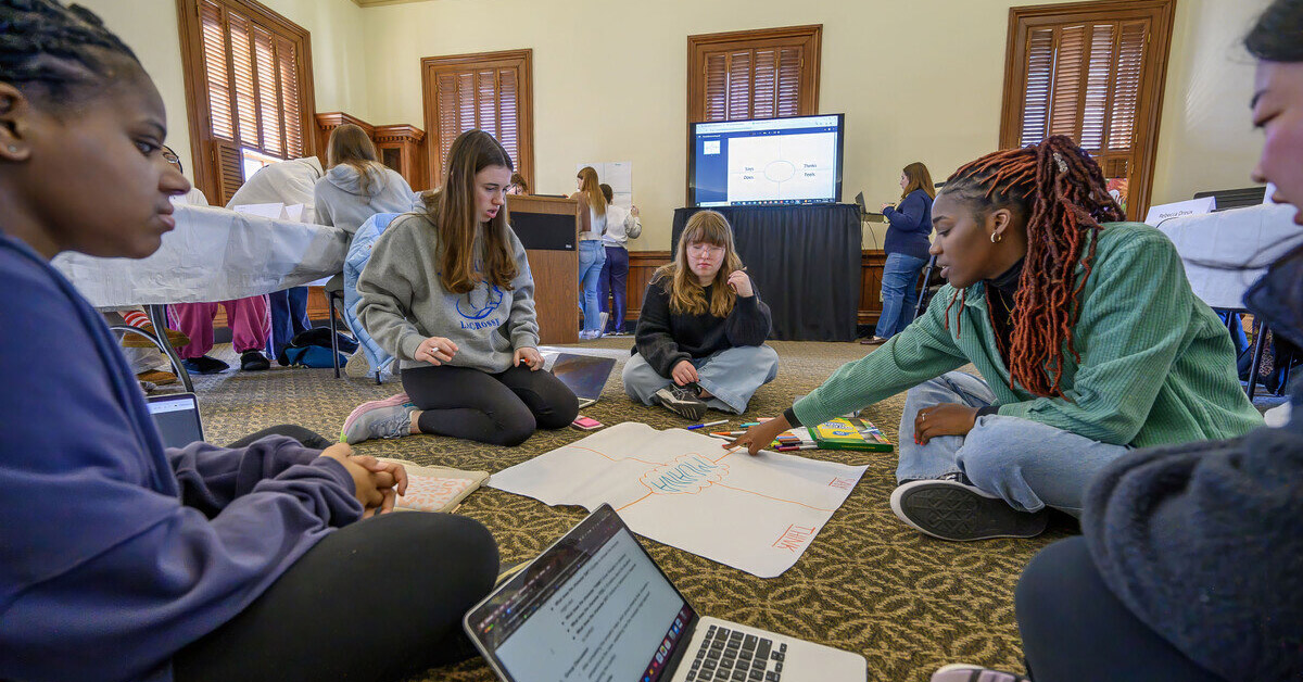 Five students sit in a circle, working on a group project.