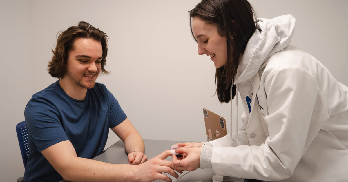 An individual affixes a sensor to the finger of the research subject.