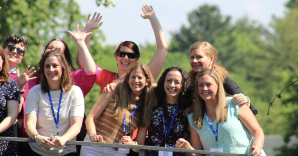 A group of eight smiling women on a sunny day.