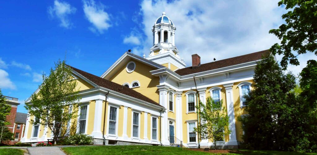 A building painted yellow with white trim and a white cupola on a sunny day.