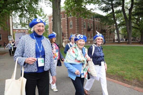 A group of women smiling and wearing blue '60 hats