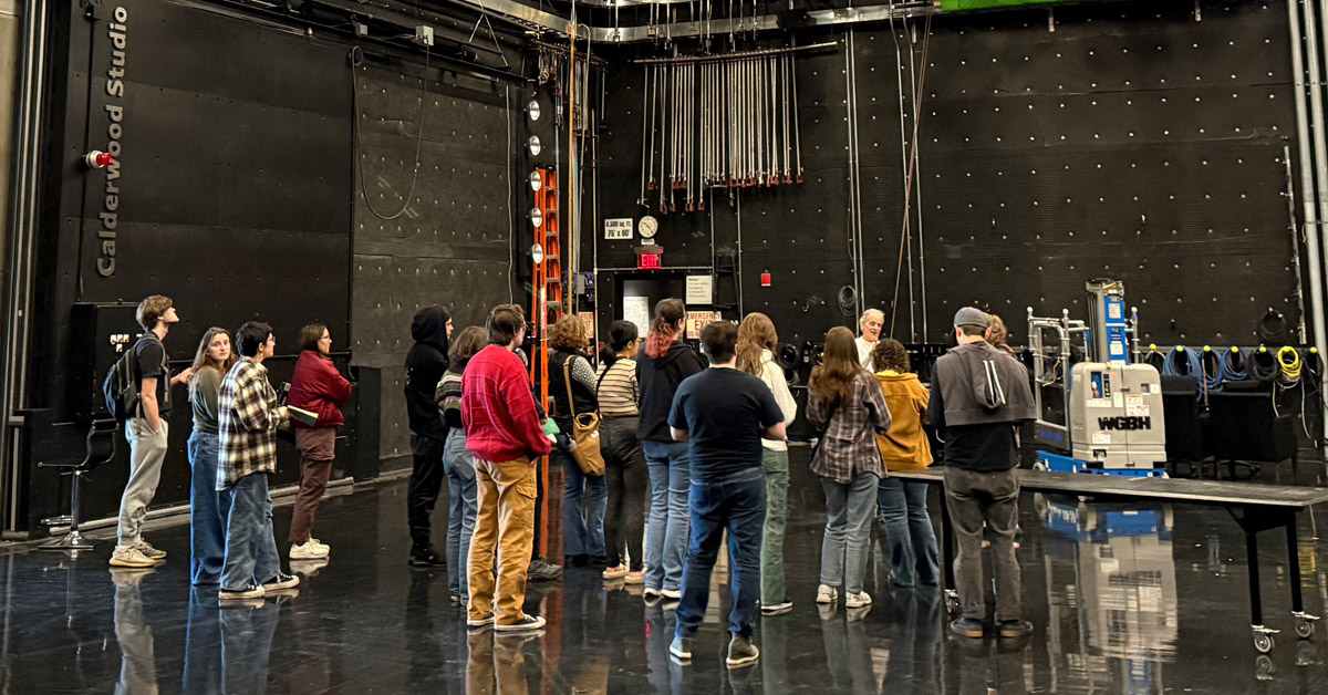 A group of a dozen individuals stand in a dark television studio.