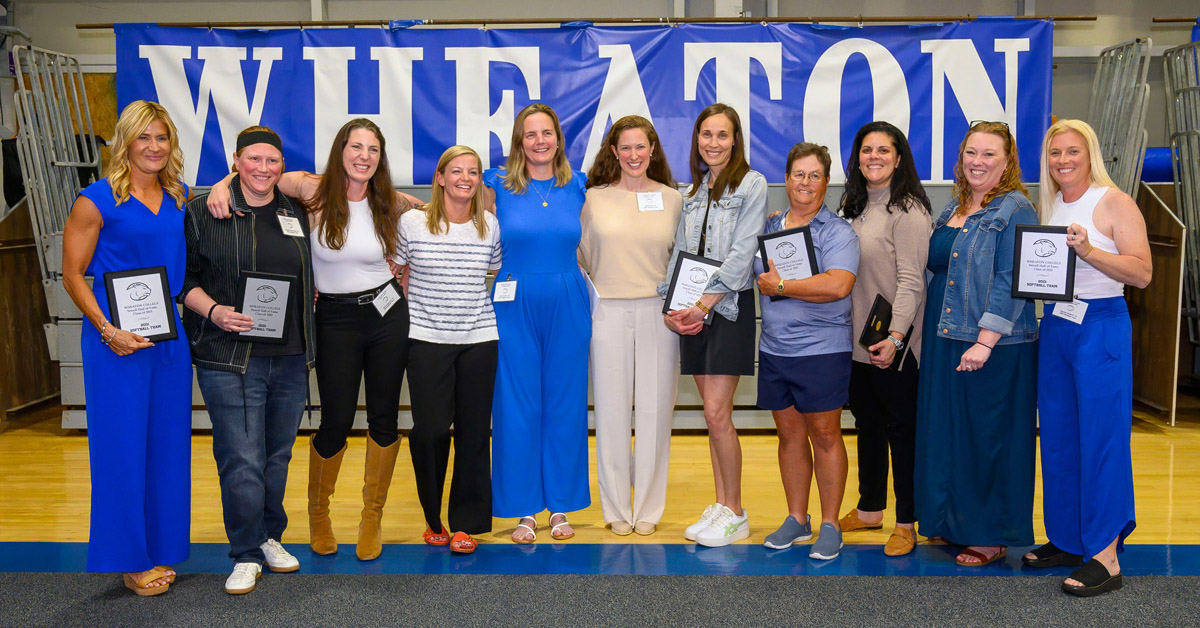 A group of a dozen women gather for a photo in front of sign reading Wheaton.