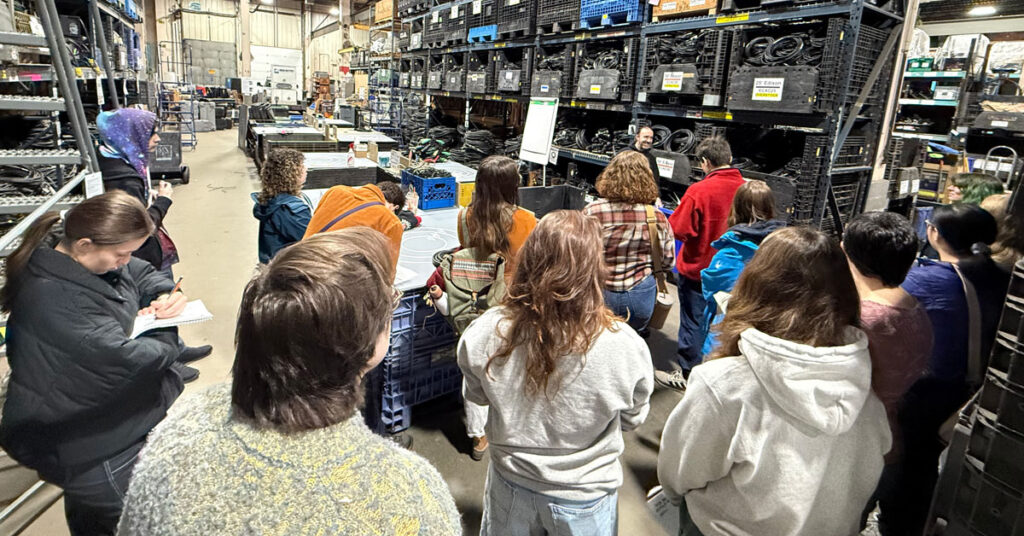 A group of young men and women observe a warehouse full of film, television and theater equipment.