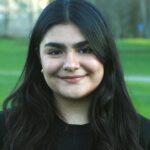 A smiling woman with long black hair wearing a black shirt