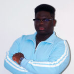 A man with short black hear wearing glasses and a light blue quarter-zip sweatshirt