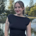 A smiling woman with brown hair wearing a black dress