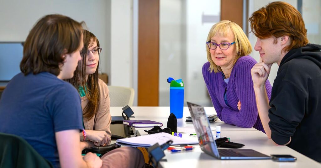 Four individuals engaged in a discussion around a table.