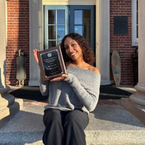 Alba Medina sits on the stairs of the library with an award she received at Honors Convocation.