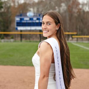Amber Arcand stands on the softball field with her Wheaton athlete graduation stole over her shoulder.