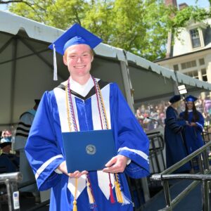 Lucas MacKenzie poses for photo with his diploma after receiving it.