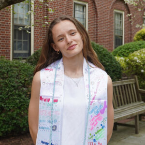 Mia Wolfgang stands in Everett Courtyard, wearing a graduation stole she decorated with friends, several days before graduation.