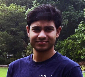 A young man with dark hair wearing a navy colored T-shirt.